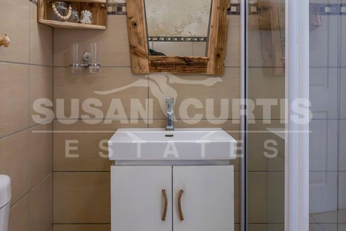 Compact bathroom featuring a vanity cabinet, shower enclosure, and tiled finishes. The walls show signs of wear and require maintenance.