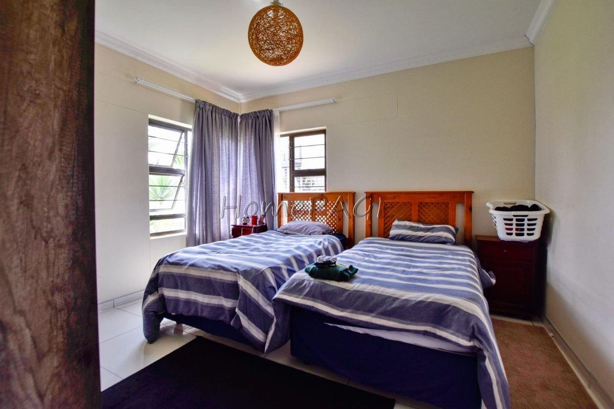A bedroom featuring tiled flooring, corner windows with security bars, and crown molding.