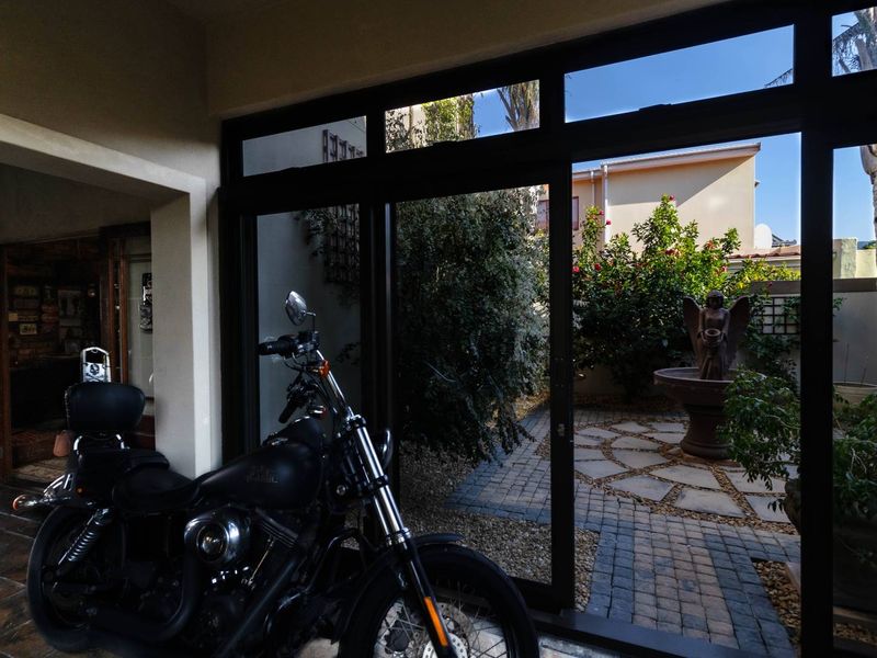 A covered patio area featuring large sliding glass doors that open onto a landscaped courtyard with a stone fountain.