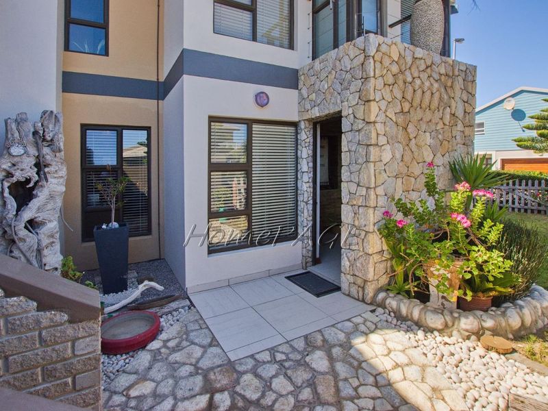 Front entrance area featuring stone cladding, tiled flooring, and modern aluminium window frames with integrated blinds.
