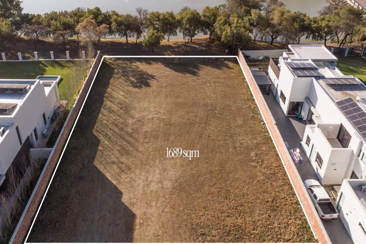 An aerial view of a 1689 sqm vacant residential plot situated between existing modern properties, featuring clear boundary lines.