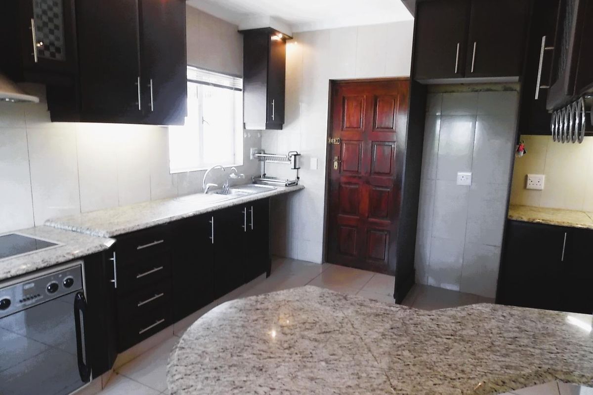 Modern kitchen featuring dark cabinetry, granite countertops, integrated oven, and a breakfast nook, providing a functional and stylish culinary space.
