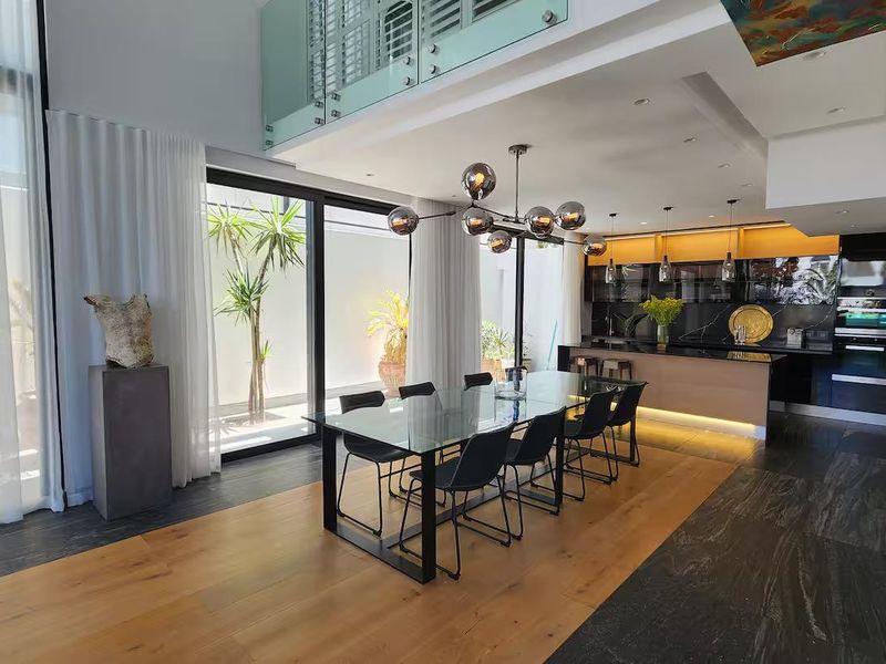 Modern open-plan living and dining area featuring high ceilings, premium kitchen cabinetry, integrated appliances, and seamless access to an outdoor patio space.