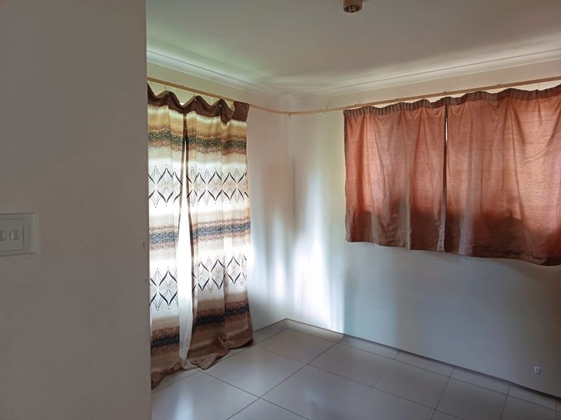 An empty bedroom featuring tiled flooring and curtain rails, offering a blank canvas for personalization.