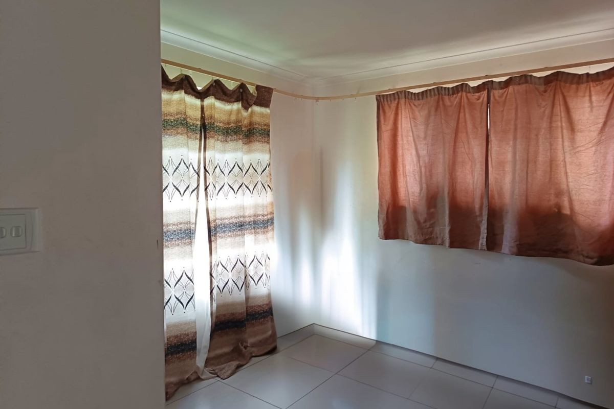 An empty bedroom featuring tiled flooring and curtain rails, offering a blank canvas for personalization.