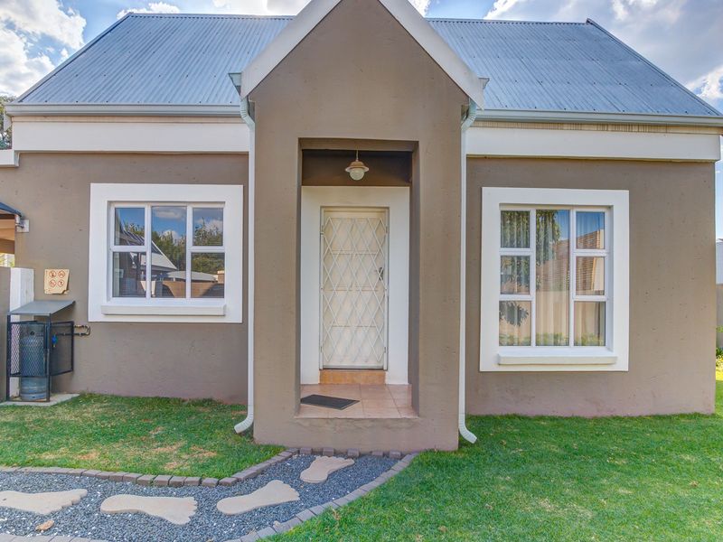 Front facade of a residential property featuring a covered entrance, corrugated metal roof, and a paved walkway leading to the front door.