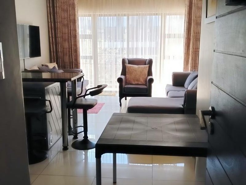 Open-plan living area featuring tiled flooring and large sliding glass doors that provide access to the balcony and allow for natural light.