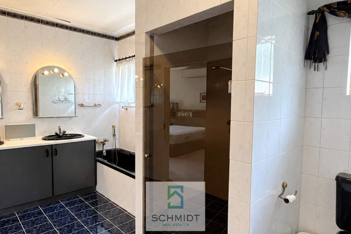 A spacious bathroom featuring a dual vanity, built-in bathtub, and a separate glass-enclosed shower with tiled finishes throughout.