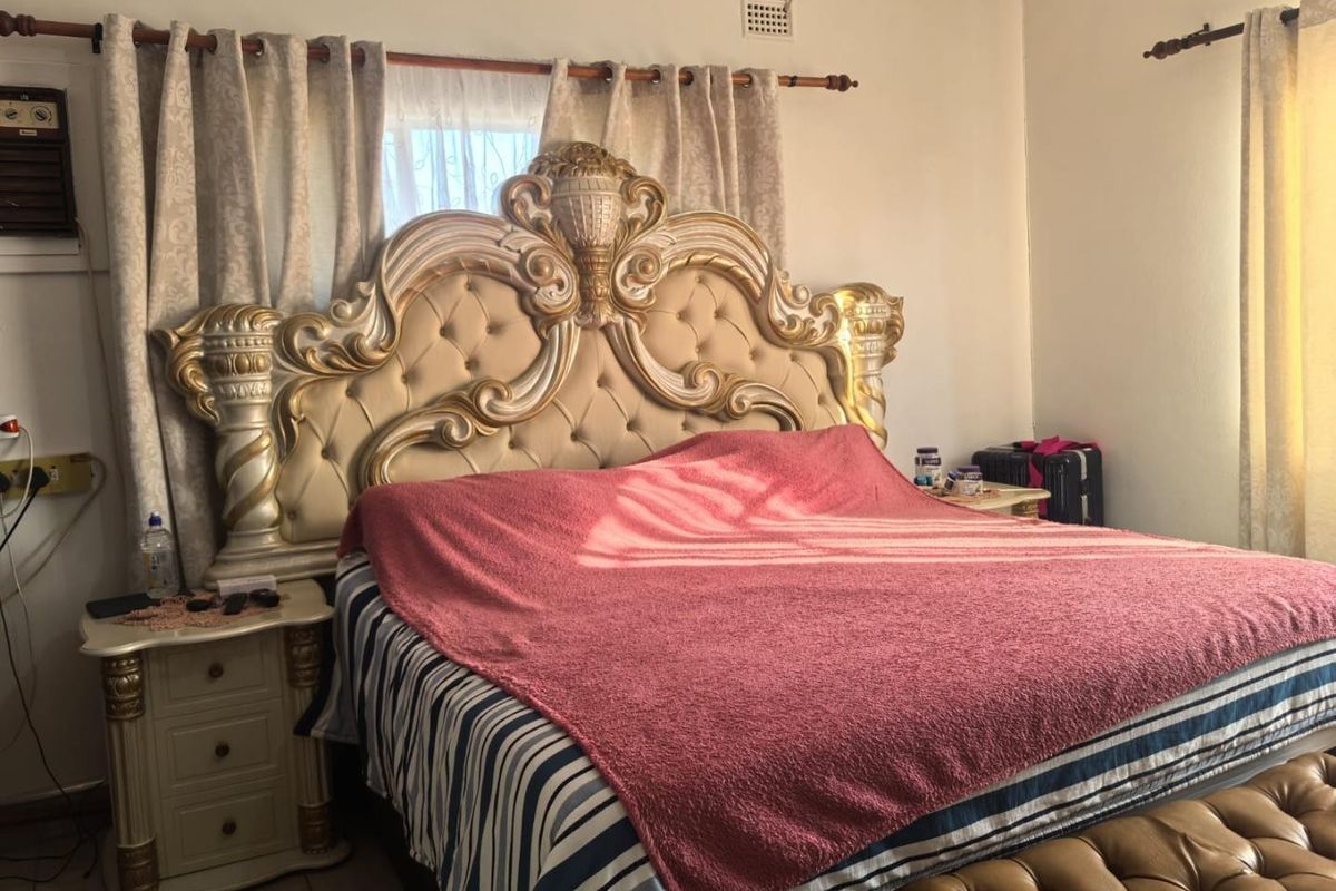A bedroom featuring a wall-mounted air conditioning unit and ventilation grille, providing basic climate control and airflow.