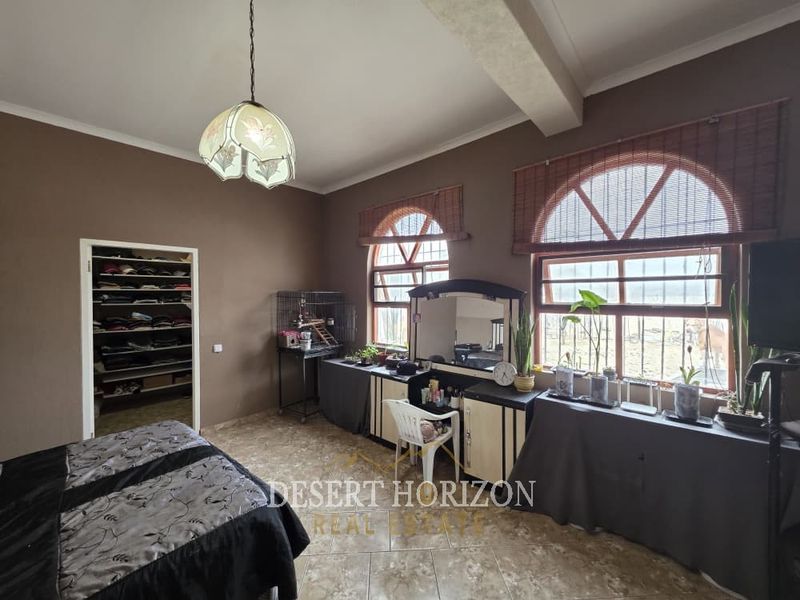 Spacious bedroom featuring distinctive arched windows, tiled flooring, and a convenient built-in closet, offering a functional layout with natural light.