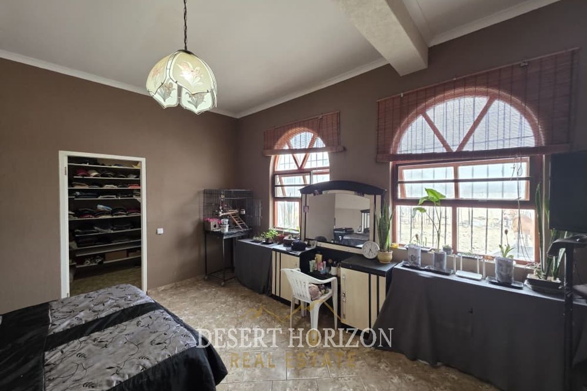 Spacious bedroom featuring distinctive arched windows, tiled flooring, and a convenient built-in closet, offering a functional layout with natural light.