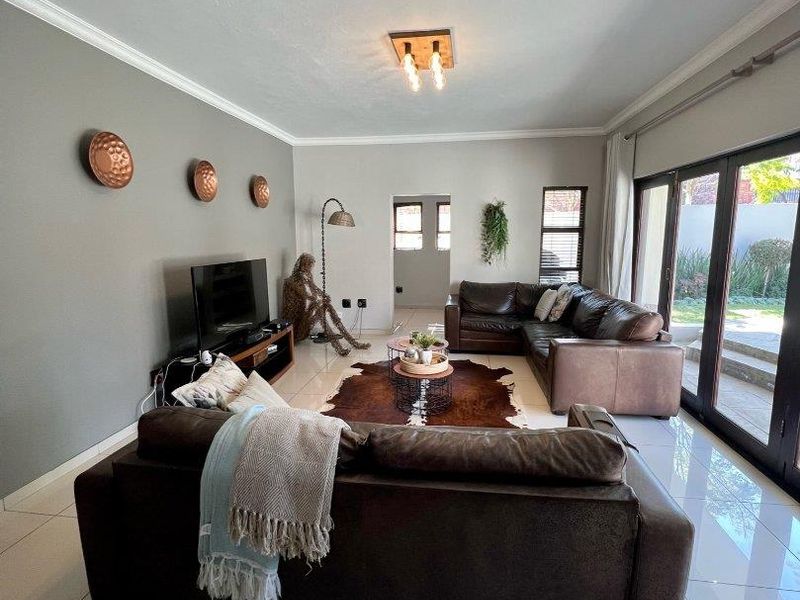 Spacious living room featuring large format floor tiles, modern ceiling lighting, and expansive sliding glass doors providing direct access to the outdoor area.