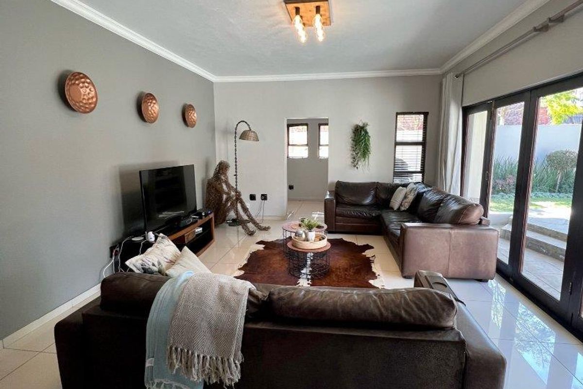 Spacious living room featuring large format floor tiles, modern ceiling lighting, and expansive sliding glass doors providing direct access to the outdoor area.