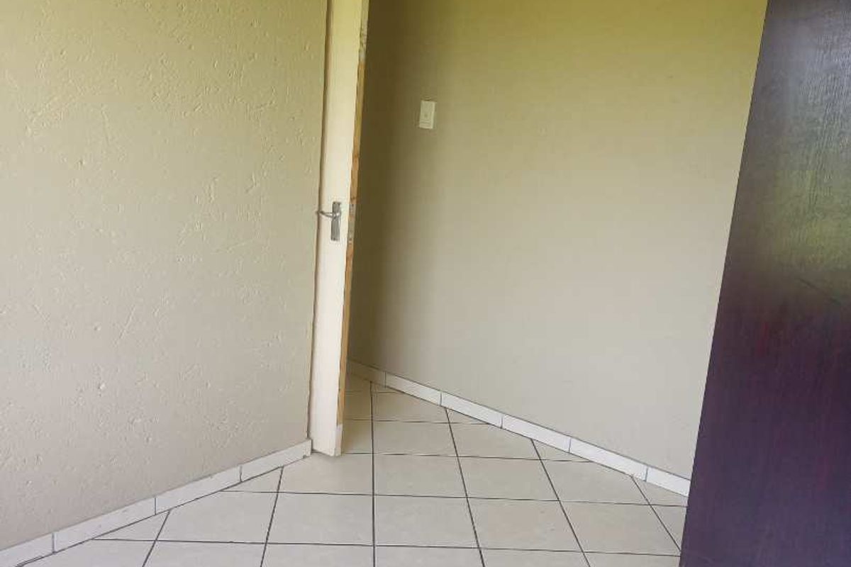 An empty bedroom featuring tiled flooring and a built-in cupboard, requiring minor cosmetic updates to refresh the space.