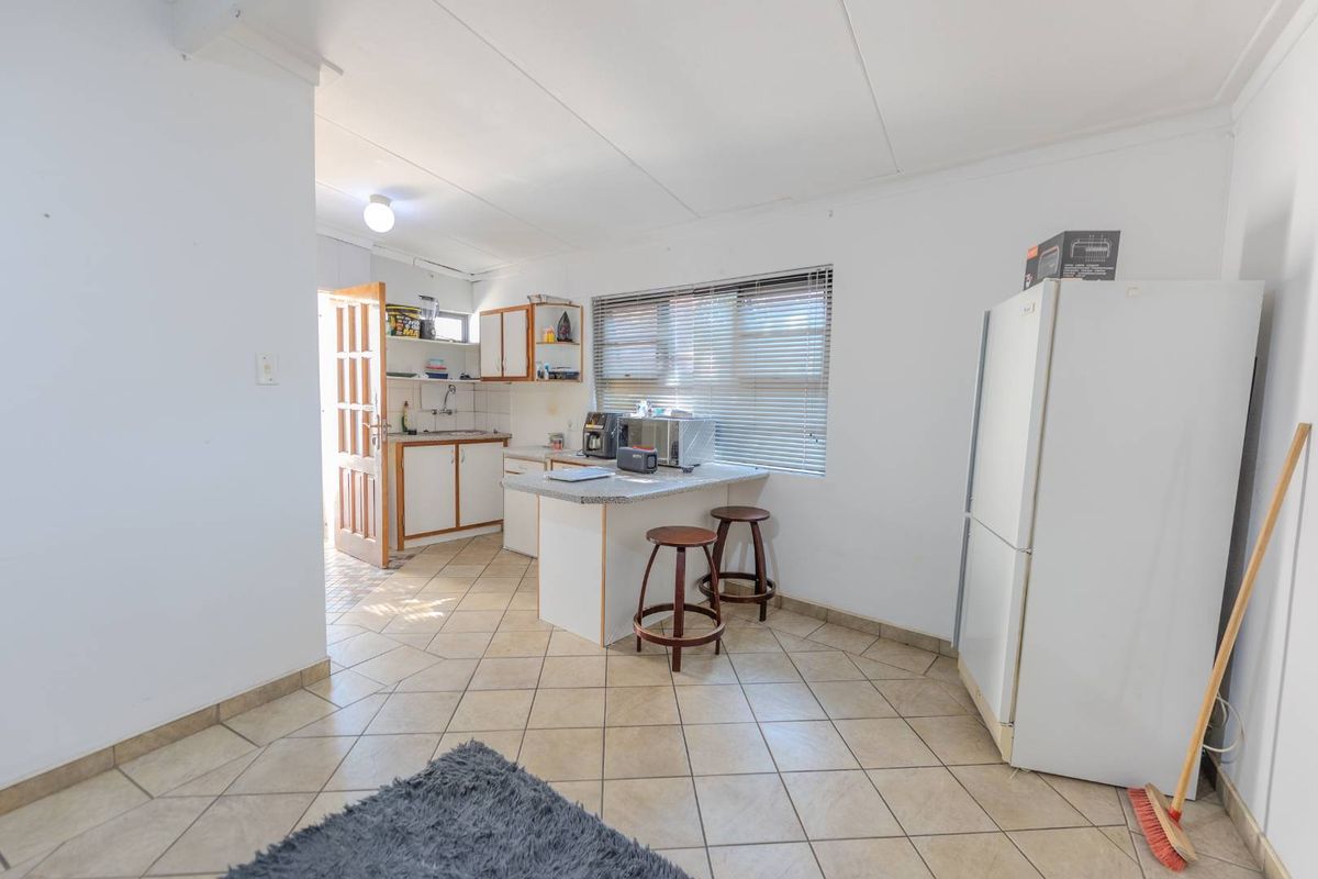 A functional kitchen area featuring tiled flooring, built-in cabinetry, and a breakfast counter, providing a practical space for meal preparation and casual dining.