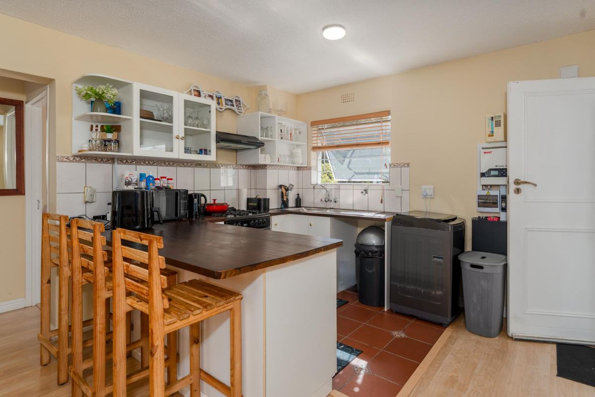 Functional kitchen featuring built-in cabinetry, a breakfast bar, tiled backsplash, and a mix of laminate and ceramic flooring.