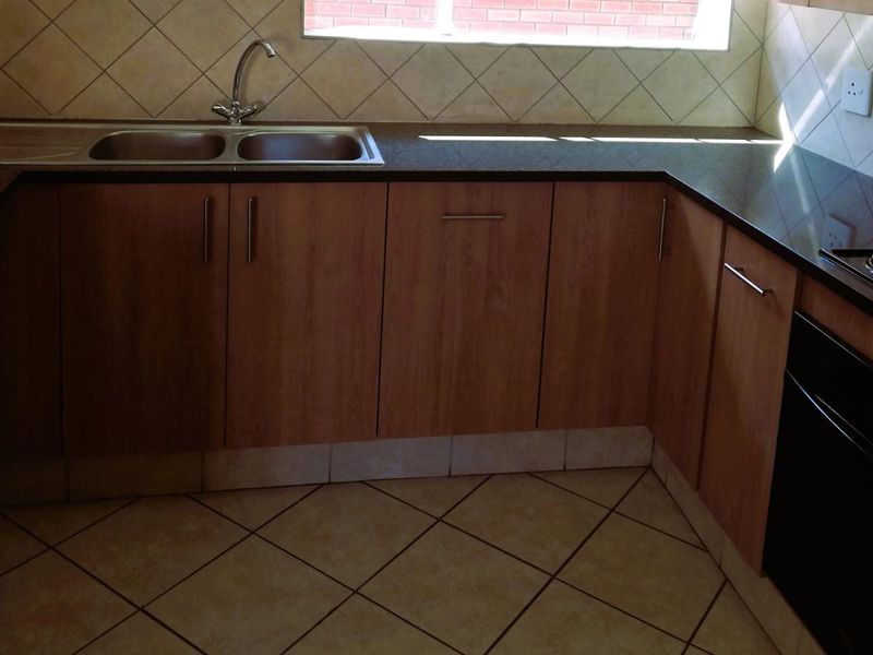 A functional kitchen featuring laminate cabinetry, granite countertops, a double bowl sink, and tiled flooring with a neutral backsplash.