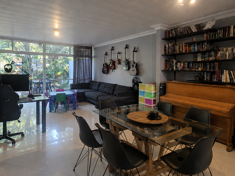 Spacious open-plan living and dining area featuring tiled floors, built-in wall shelving, and large glass doors providing natural light and garden access.