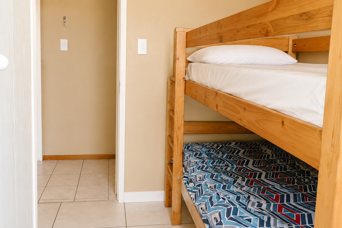 A bedroom featuring tiled flooring and neutral wall paint, currently furnished with a wooden bunk bed.