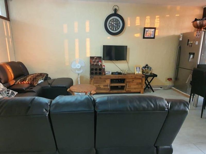 Open plan living and dining area featuring tiled flooring and textured wall finishes, providing a functional space for relaxation and meals.