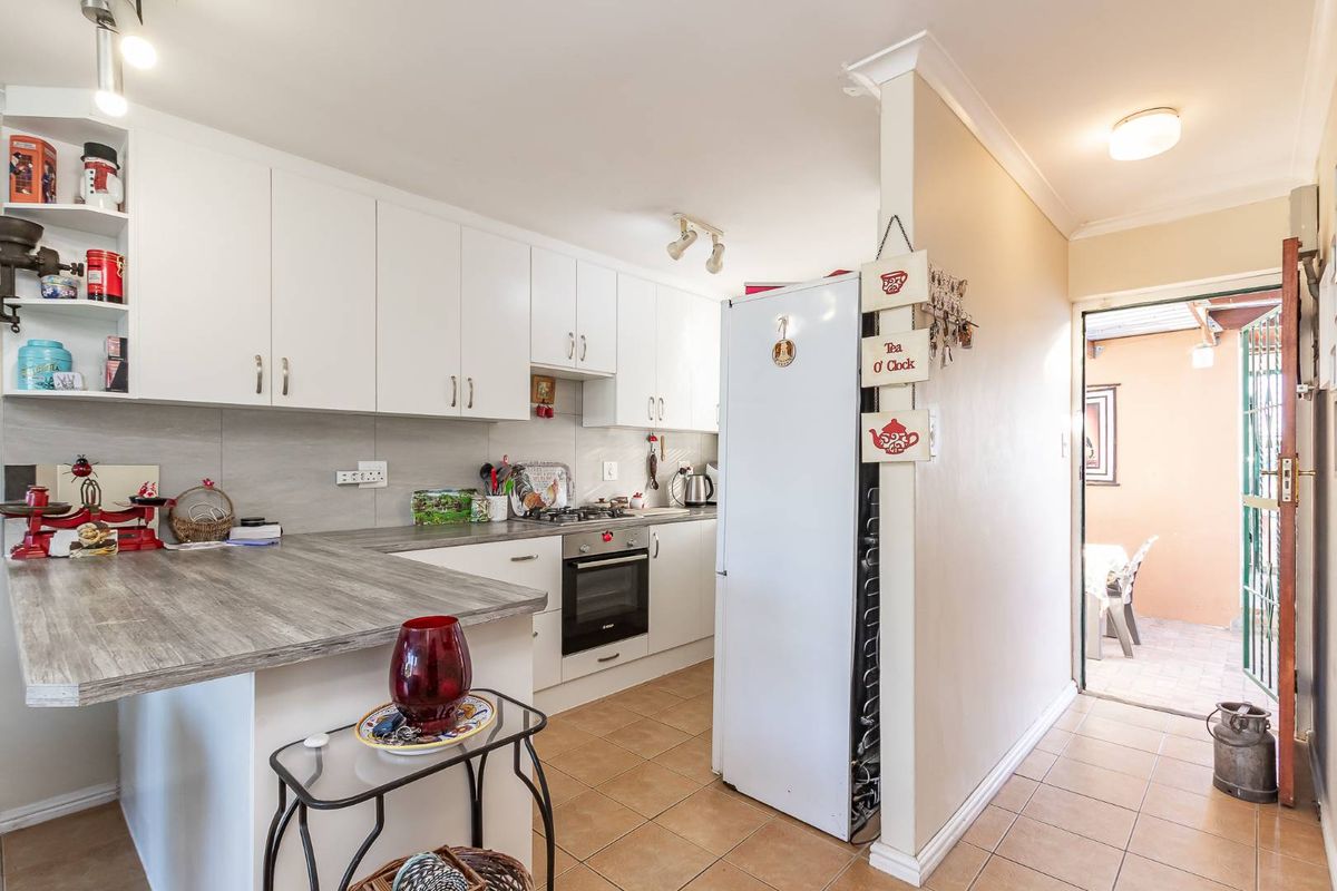A functional kitchen featuring white cabinetry, wood-look laminate countertops, a built-in oven, and a gas hob, with direct access to an outdoor patio area.