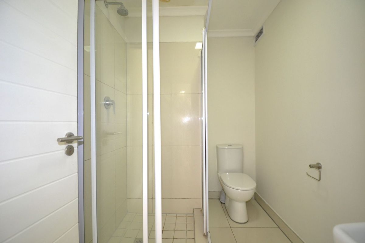 A functional bathroom featuring a glass-enclosed shower cubicle and a standard white toilet suite with tiled flooring.