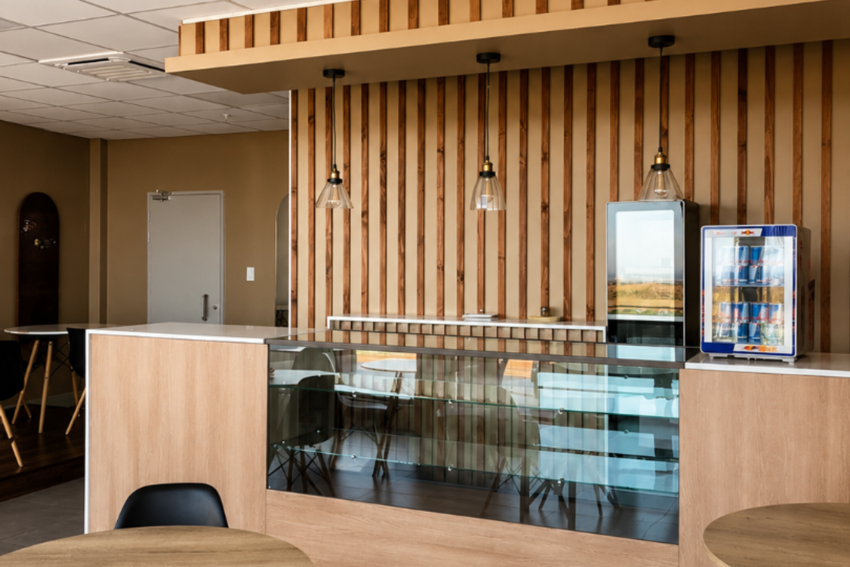 A modern retail service area featuring a glass display counter, timber slat wall accents, pendant lighting, and a suspended ceiling with tiled flooring.