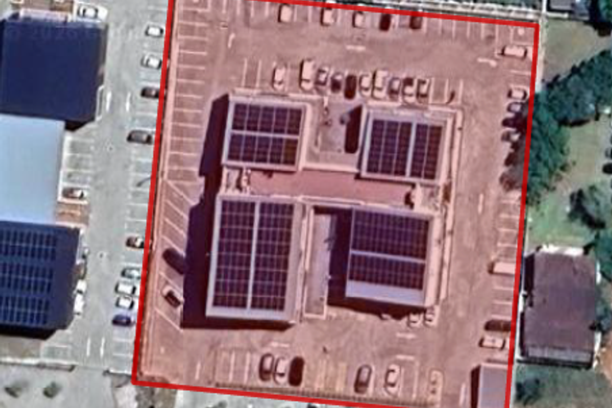 Aerial view of the property showing the building roof with installed solar panels and the surrounding paved parking lot.
