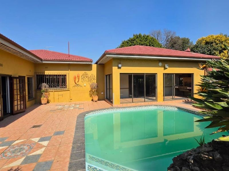Rear exterior view featuring a swimming pool, tiled patio area, and direct access to the home through sliding glass doors.