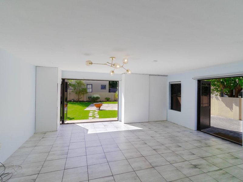 Spacious, light-filled living area featuring tiled flooring and large sliding doors providing seamless access to the rear garden.