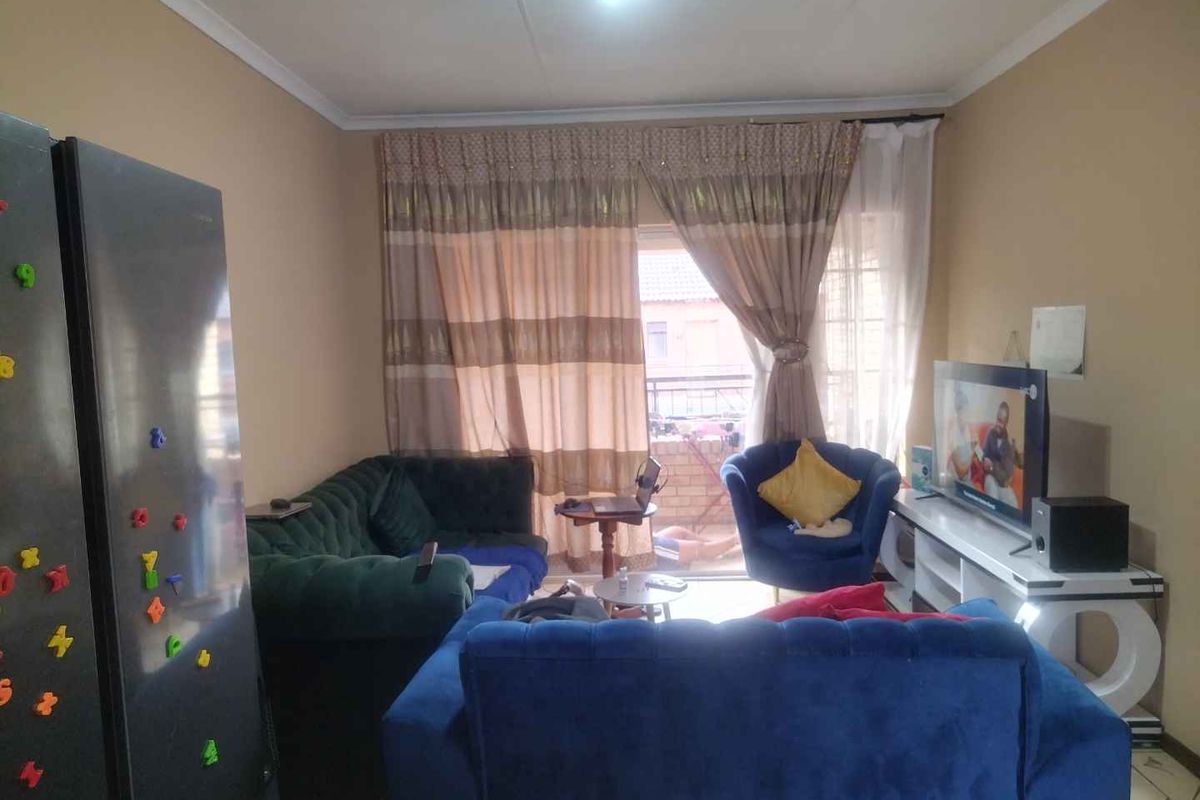 A living room area featuring tiled flooring and a sliding glass door providing access to an outdoor space.