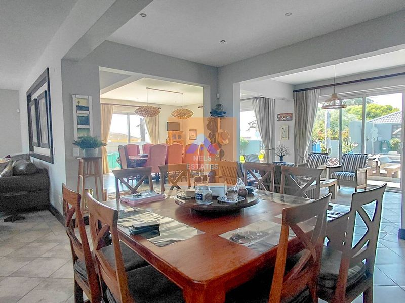 Spacious open-plan living and dining area featuring tiled flooring, recessed lighting, and large sliding glass doors providing access to the outdoor patio.