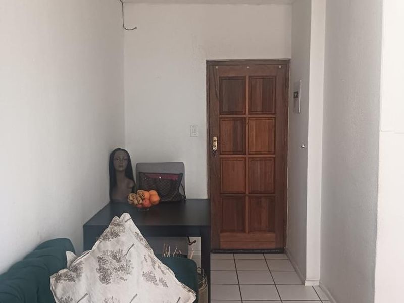 An entry area featuring tiled flooring and a traditional timber panelled door, with visible electrical wiring requiring attention.