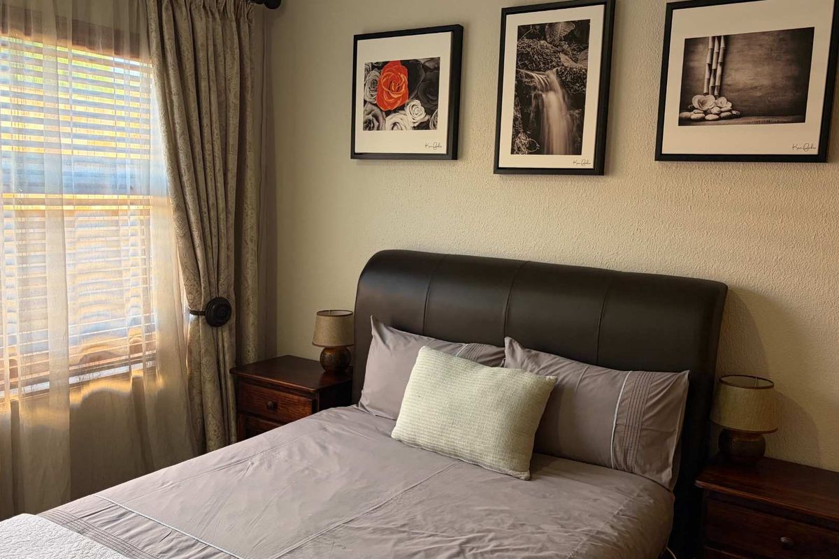 A well-maintained bedroom featuring neutral wall finishes and natural light through a window with installed curtain rods.