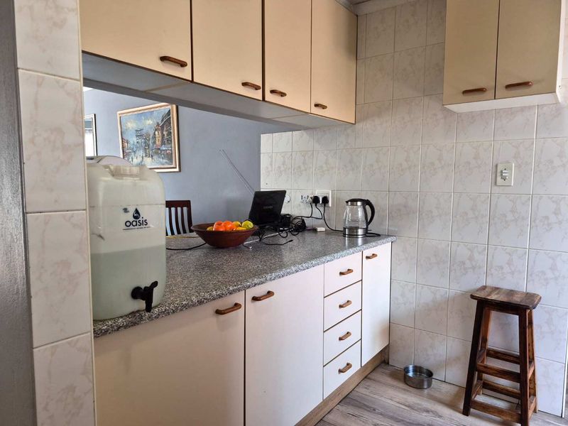 A functional kitchen area featuring laminate cabinetry, granite-look countertops, and tiled splashbacks, offering a practical layout for daily meal preparation.