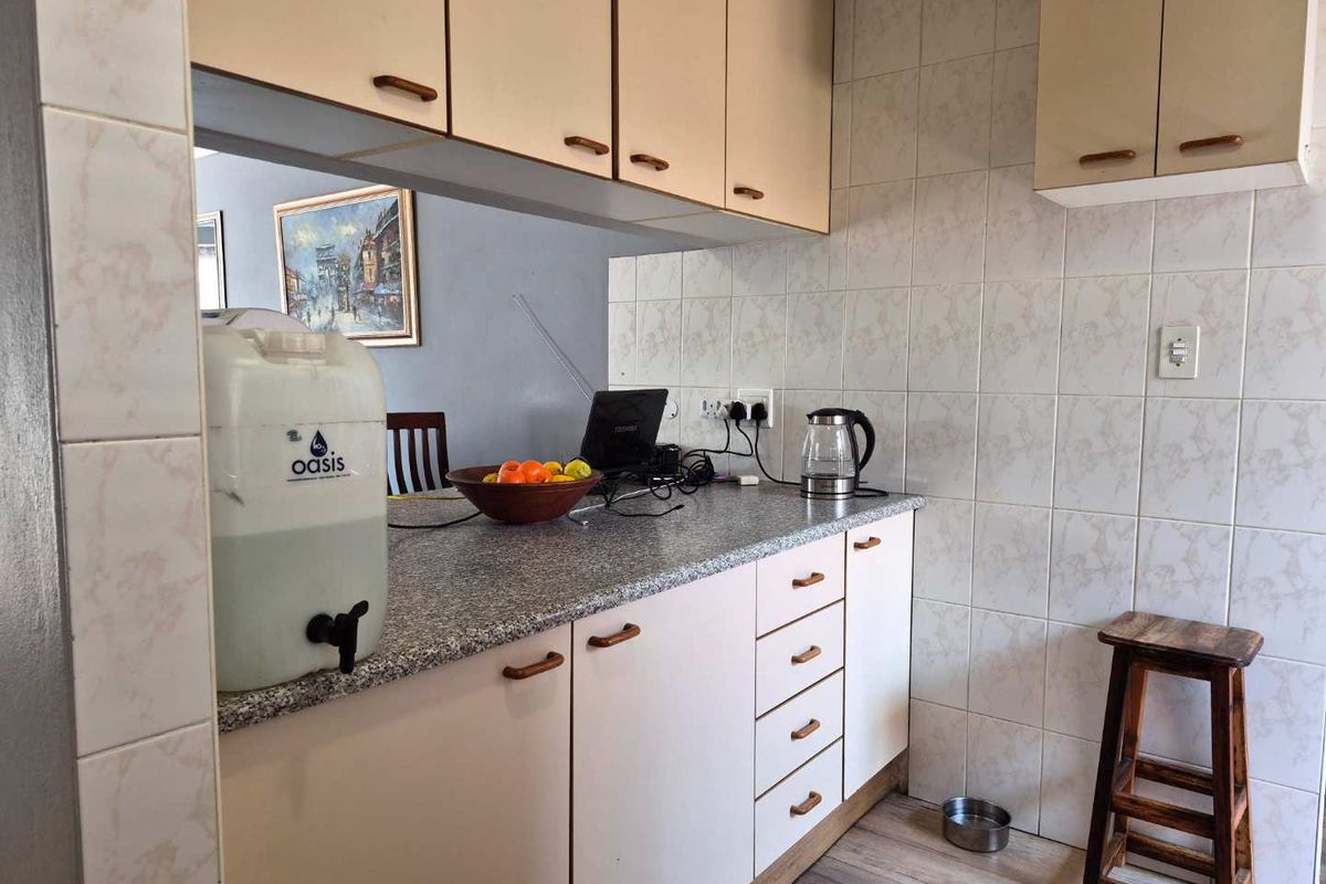 A functional kitchen area featuring laminate cabinetry, granite-look countertops, and tiled splashbacks, offering a practical layout for daily meal preparation.