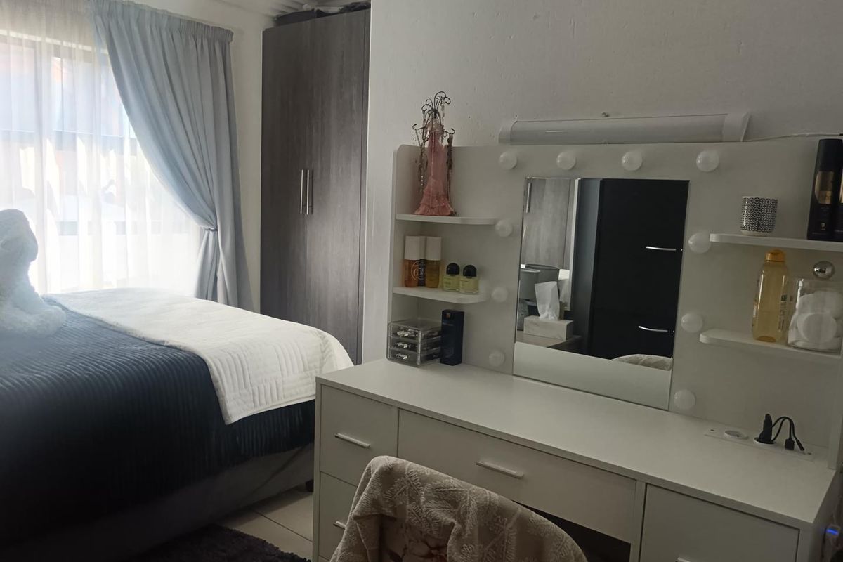 A bedroom featuring tiled flooring and a built-in wardrobe, with natural light entering through a window.