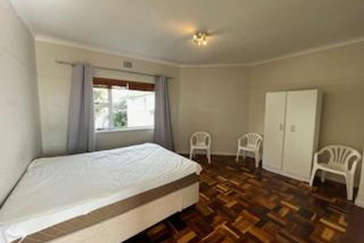 A spacious bedroom featuring classic parquet flooring, neutral walls, and a ceiling light fixture, offering a clean and functional living space.
