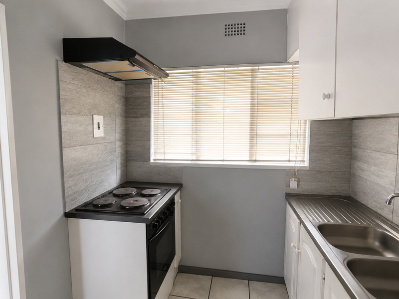 A clean, functional kitchen featuring built-in cabinetry, a double bowl sink, and an electric stove with an extractor fan.