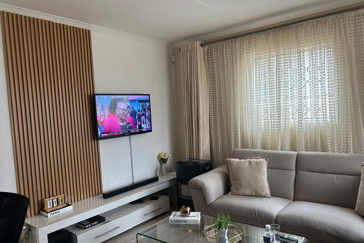 A well-maintained living room featuring a decorative timber slat feature wall, built-in media console, and large window with integrated curtain tracks.