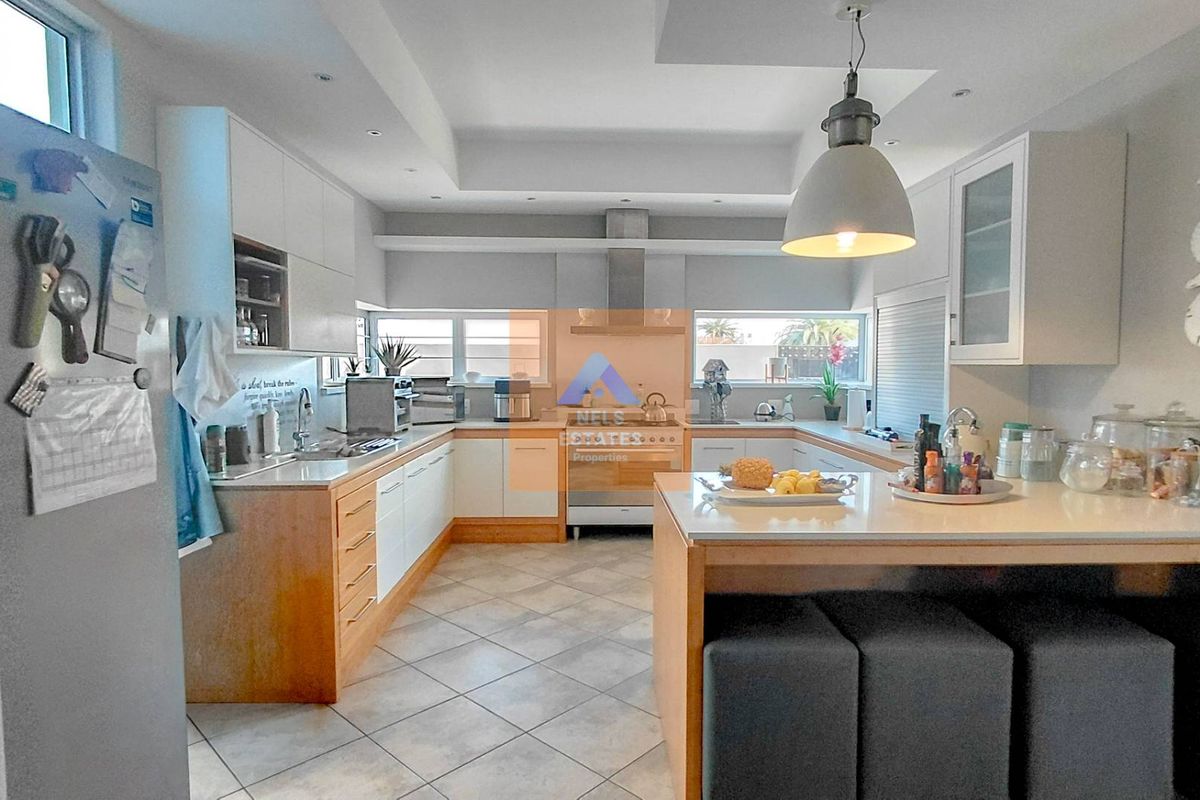 Modern kitchen featuring a functional u-shaped layout, central island with breakfast bar, stone countertops, and integrated stainless steel appliances.