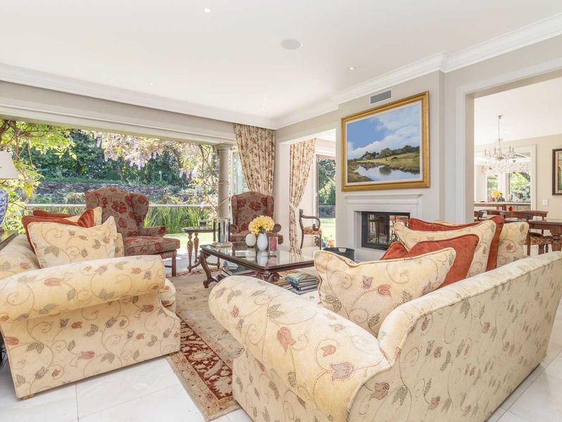 Spacious living room featuring a fireplace, crown molding, and large sliding glass doors that open to a garden view.