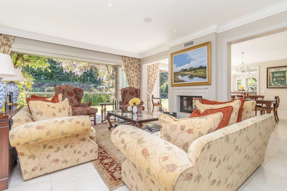Spacious living room featuring a fireplace, crown molding, and large sliding glass doors that open to a garden view.