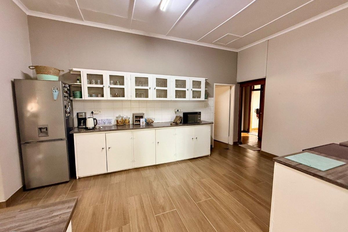 A functional kitchen featuring white cabinetry, tiled backsplash, and wood-look floor tiles, providing ample storage and workspace.