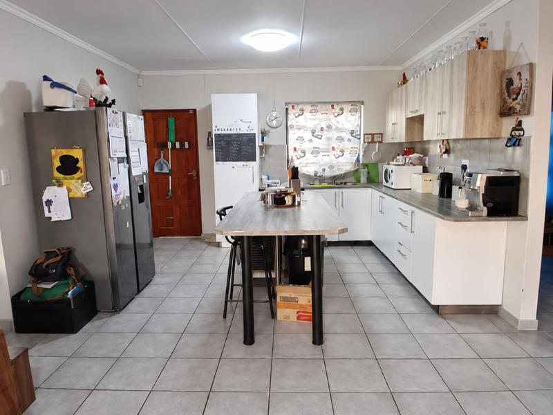A functional kitchen featuring a central island, ample built-in cabinetry, tiled flooring, and a tiled backsplash, providing a practical workspace.