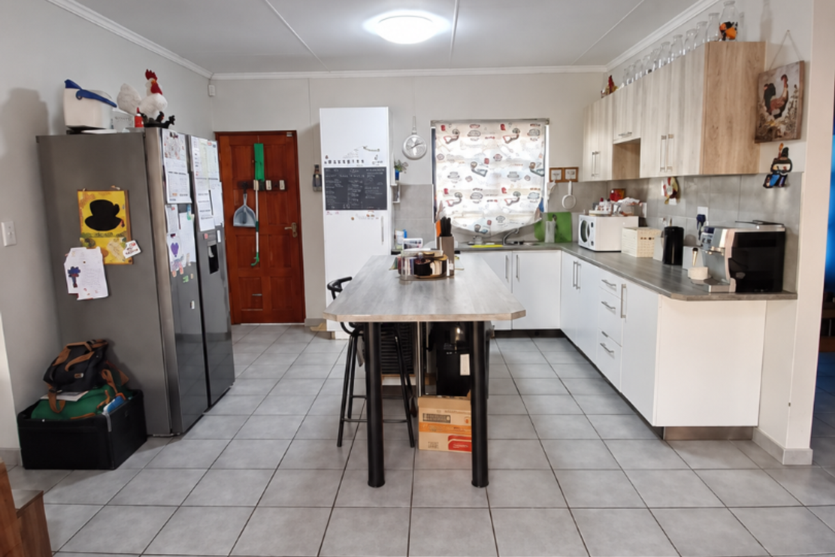 A functional kitchen featuring a central island, ample built-in cabinetry, tiled flooring, and a tiled backsplash, providing a practical workspace.