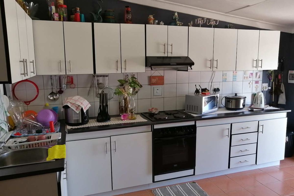 A functional kitchen featuring white cabinetry, dark countertops, a built-in oven with extractor fan, and tiled flooring.