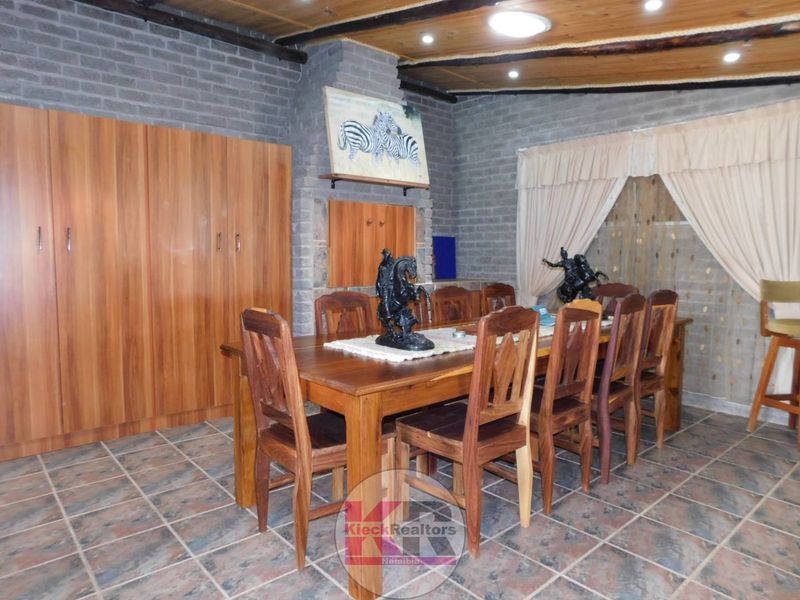 Dining room featuring exposed brick walls, timber ceiling, tiled flooring, and built-in cabinetry, offering a rustic and functional space for family meals.
