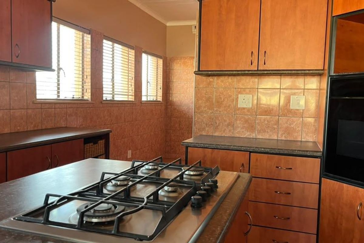 A functional kitchen featuring wood-finish cabinetry, laminate countertops, a built-in gas hob, and an integrated oven with tiled splashbacks.