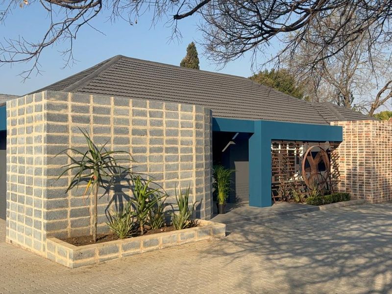 Modern commercial property exterior featuring a unique concrete block facade, tiled roof, and a paved driveway with a built-in planter box.